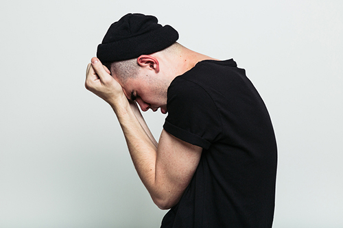 Side view of emotional man regretting posing on white studio background.